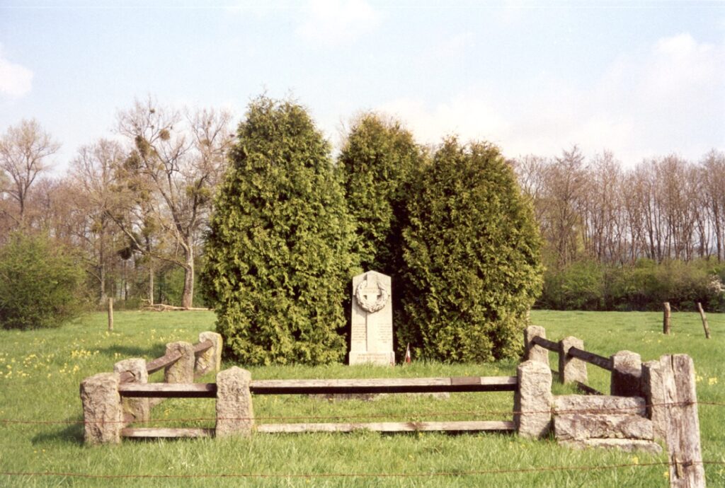 Captain Hamilton Coolidge's original graveyard is pictured as a single monument with three tall trees behind it surrounded by a wooden fence.